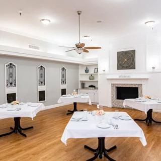 A modern dining room with neatly arranged tables and a cozy fireplace.