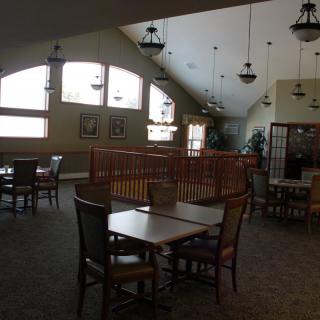 A spacious dining area with tables and chairs, featuring large windows and decorative lighting.