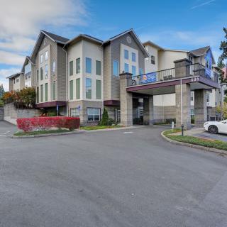 A modern residential apartment complex with a parking area in a suburban setting.