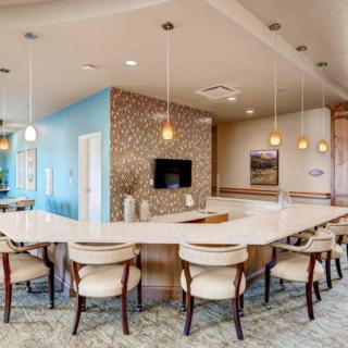 A modern kitchen with a spacious dining area and bar seating, featuring pendant lighting and stylish decor.