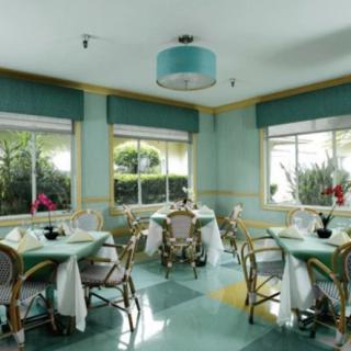 A bright and airy dining area with tables and chairs, surrounded by windows letting in natural light.