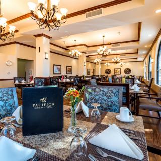 An elegant restaurant dining room with set tables and chandeliers.