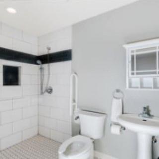 A modern bathroom with a walk-in shower, toilet, and pedestal sink.
