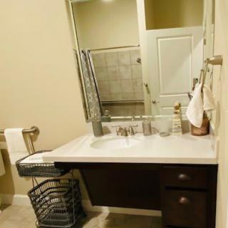 A tidy bathroom with a modern sink, large mirror, and neatly arranged towels.