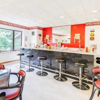 A retro-style diner with red and white decor, featuring a classic countertop and bar stools.