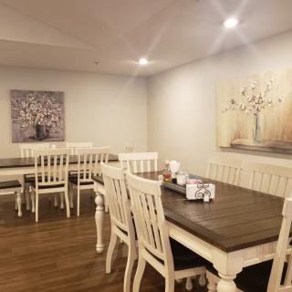 A cozy dining area featuring wooden tables and chairs, complemented by soft lighting and elegant artwork on the walls.