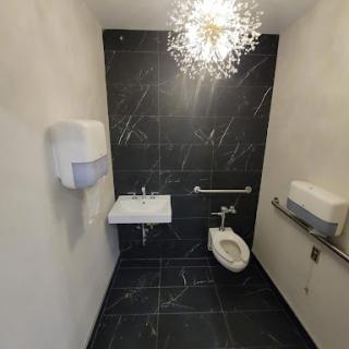 A modern bathroom featuring sleek black tiles and elegant lighting.