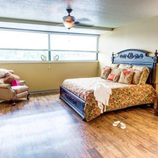 A cozy bedroom with a large bed, an armchair, and ample natural light from the window.