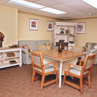 A cozy living room with a central table and chairs surrounded by a sofa and decorative shelves.