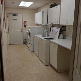 A clean and organized laundry room with a washer, dryer, cabinets, and a sink.