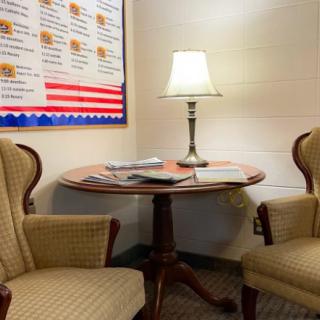 Cozy office waiting area with two chairs, a small table, and a lamp.