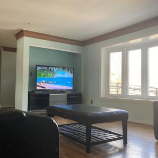 A cozy living room with a television and a view through large windows.