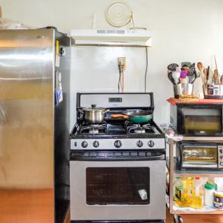 A well-used kitchen featuring a stove with pots, a refrigerator, and various cooking utensils.