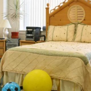 A cozy bedroom with a neatly made bed and colorful balls on the floor.