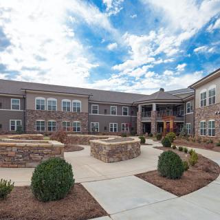 A view of a modern building with a landscaped courtyard under a partly cloudy sky.