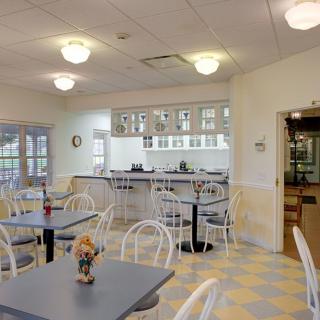 A cozy cafe interior with tables and chairs arranged in a well-lit room.