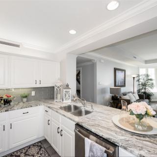 A modern kitchen with white cabinets and granite countertops, featuring an open-concept layout.