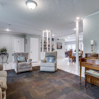 A modern living room with comfortable armchairs and a view into the dining area.