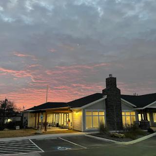 A serene sunset illuminates the exterior of a building, highlighting its architectural features against a dramatic sky.