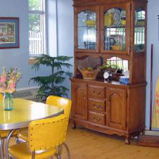 A cozy dining room with yellow chairs and a wooden cabinet, complemented by decor and an indoor plant.