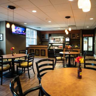 A cozy and modern cafe interior with tables and chairs arranged neatly under warm lighting.