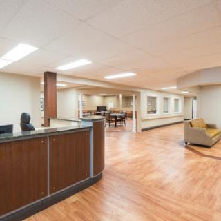 A modern office reception area featuring a counter, seating, and a spacious layout.