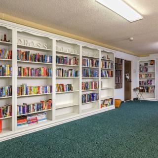 A quiet library room with white bookshelves filled with books.
