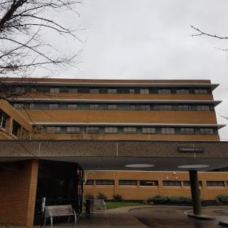 A modern building with a cloudy sky overhead, showcasing an institutional architectural style.
