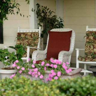 A cozy porch setup with wicker chairs and blooming flowers.
