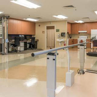 A spacious rehabilitation center featuring exercise equipment, including parallel bars for physical therapy.