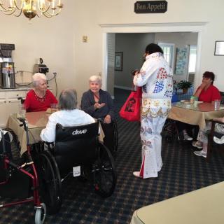 A performer in costume interacts with elderly residents at a nursing home.