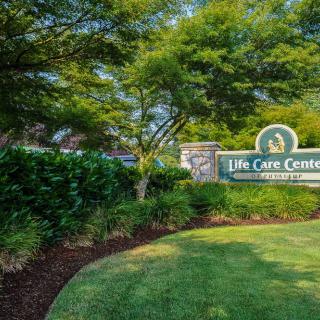 Entrance sign for the Life Care Center surrounded by lush greenery and well-maintained landscaping.