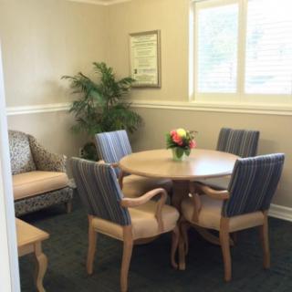 A cozy conference room with a round table and several chairs, featuring a potted plant and a window for natural light.