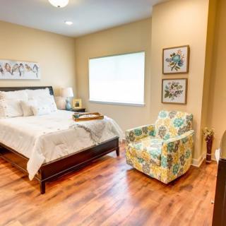 A cozy bedroom with a bed, colorful armchair, and decorative wall art.