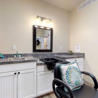 A clean and organized hair salon station featuring a styling chair, mirror, and sink.