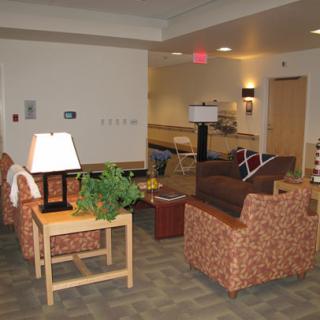A cozy waiting room with comfortable seating, lamps, and an indoor plant.
