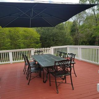 A peaceful outdoor patio with a table, chairs, and an umbrella overlooking lush greenery.