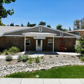 A single-story building with a well-maintained front yard and clear blue sky.