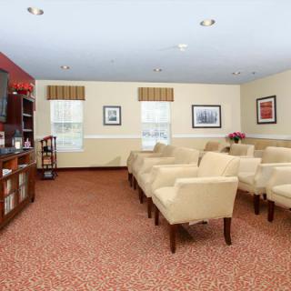 A cozy living room with rows of comfortable seating, a television, and framed artwork on the walls.