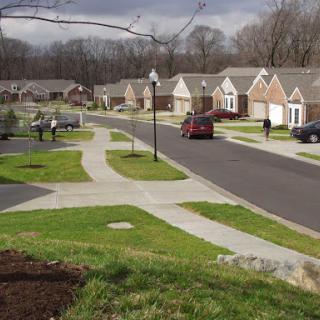 A quiet suburban neighborhood featuring lined houses, well-maintained sidewalks, and a winding road.
