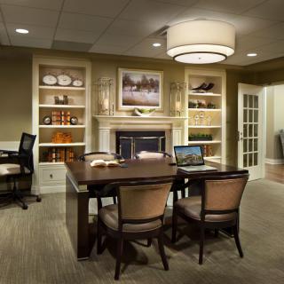 A modern office conference area with a large table, chairs, and built-in bookshelves.