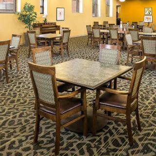 A spacious dining area featuring wooden tables and chairs, accented by a patterned carpet.