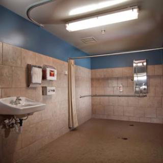 A view of a spacious bathroom featuring tiled walls, a sink, and overhead lighting.
