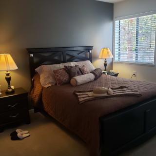 A cozy bedroom with a neatly made bed, complete with decorative pillows and matching lamps on each side.