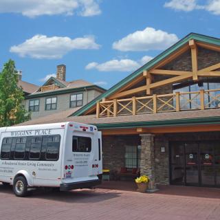 A shuttle bus parked outside a large building with rustic architectural features.