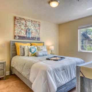 A cozy bedroom with stylish decor, featuring a neatly made bed and colorful artwork on the wall.