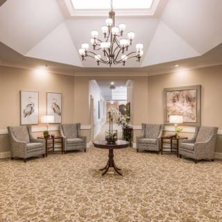 A well-lit lobby with a central chandelier, comfortable seating, and decorative artwork on the walls.