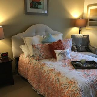 A cozy bedroom with a well-decorated bed and warm lighting.