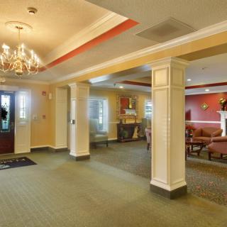 A spacious lobby with elegant columns, a chandelier, and comfortable seating.