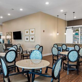 A modern dining area with neatly arranged tables and chairs, featuring stylish lighting and decor.
